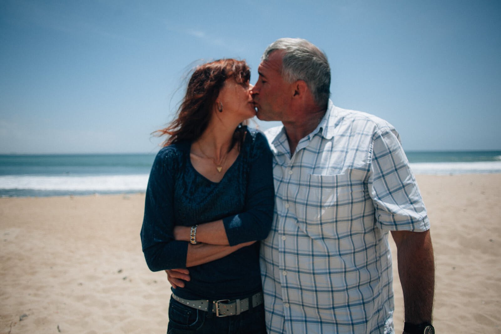 Couple kissing on the beach for a family photo session